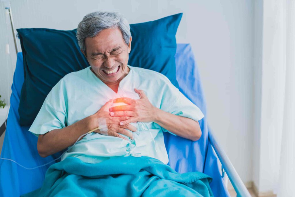 Old senior on a hospital bed clutching his chest in pain.